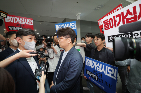 한동훈 법무부 장관의 2022년 4월 국회 인사청문회 당시 개인정보 유출 의혹과 관련 MBC 기자 임모씨를 압수수색 중인 경찰(왼쪽)이 30일 상암동 MBC 사옥 진입을 시도하자 MBC 노조원들이 항의하고 있다.<연합뉴스>